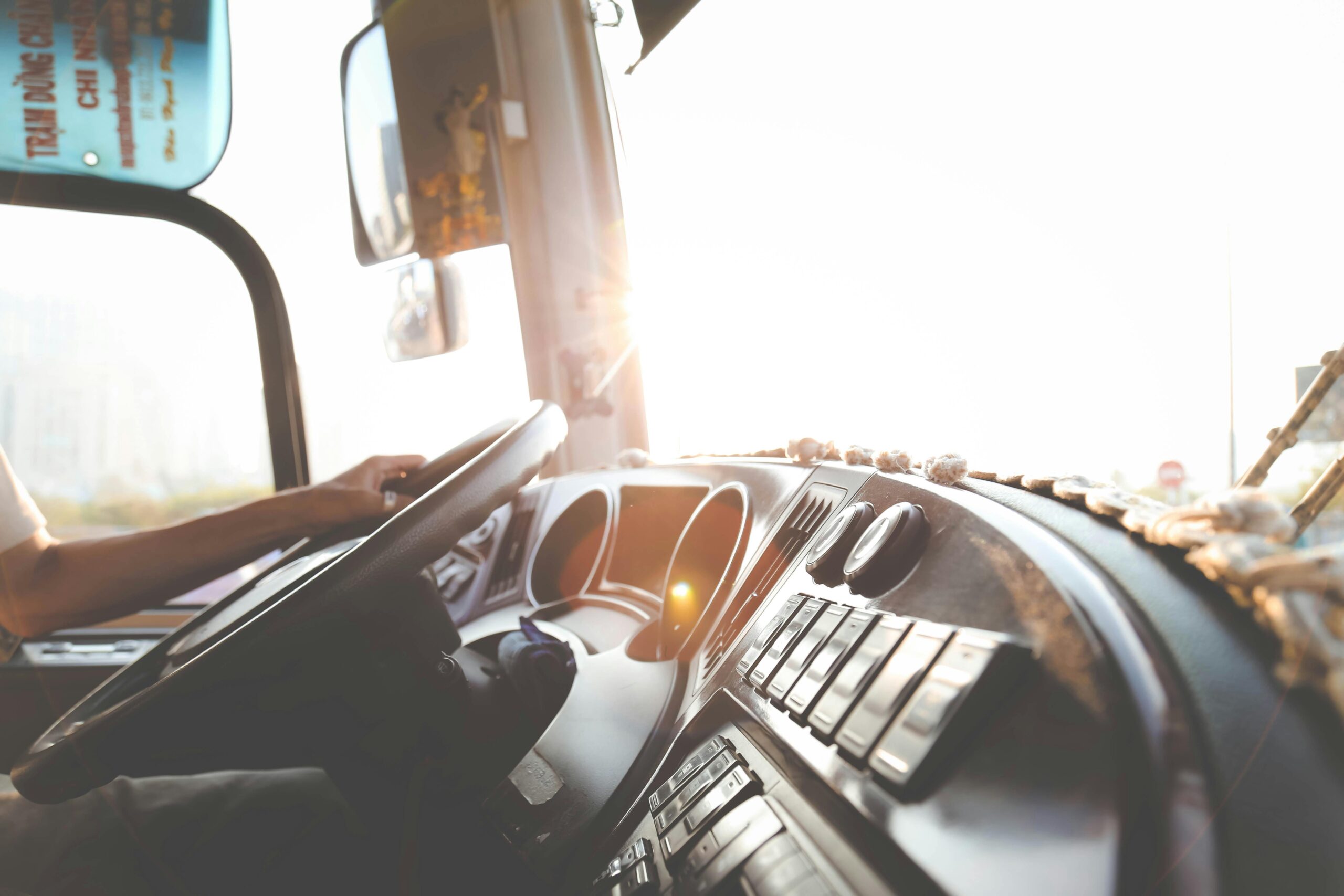 A bus driver navigating the city streets during a sunny day, focusing on the road.